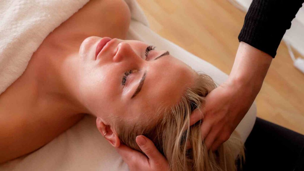 Kvinde der under en ansigtsbehandling får hovedbunds massage