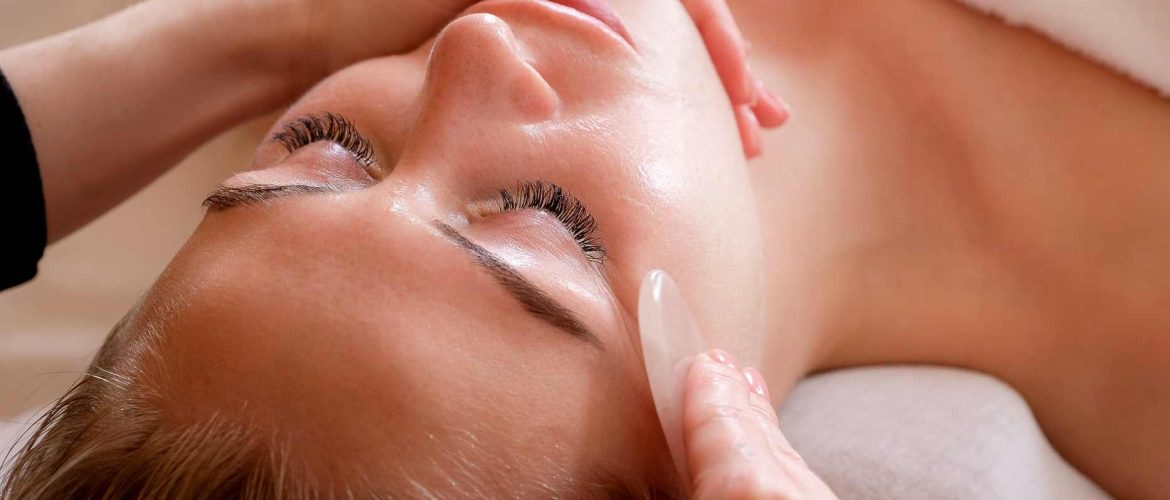 Kvinde får afslappende gua sha massage med en rosakvarts sten under ansigtsbehandling/facial i klinik på Nørrebro